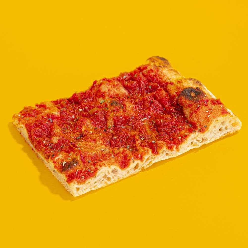 Trancio di pizza rossa con origano su fondo giallo